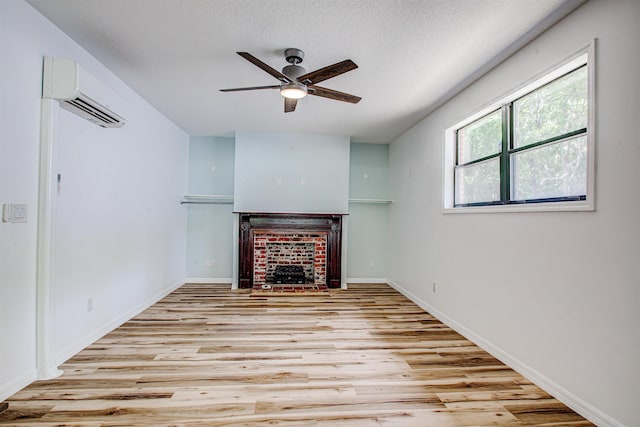 unfurnished living room featuring wood finished floors, an AC wall unit, a ceiling fan, baseboards, and a fireplace