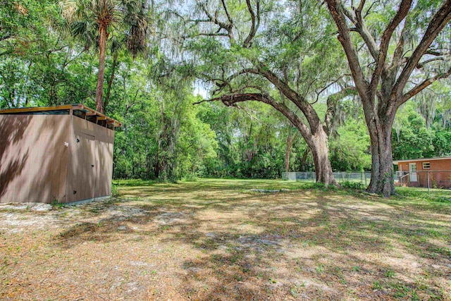 view of yard with fence, an outdoor structure, and a storage shed