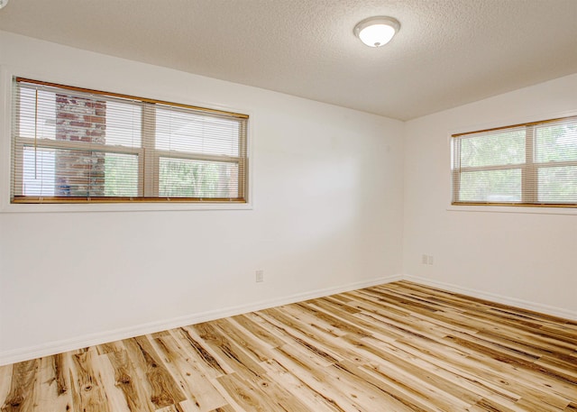 empty room featuring baseboards, wood finished floors, and a textured ceiling