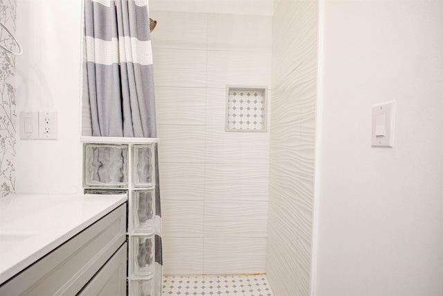 full bath featuring vanity and tiled shower
