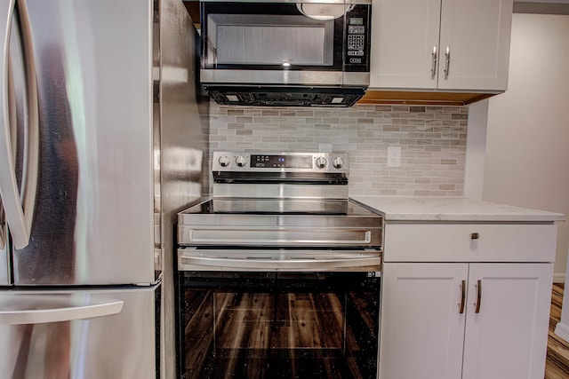 kitchen featuring light stone counters, tasteful backsplash, appliances with stainless steel finishes, and white cabinetry