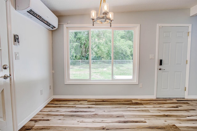 unfurnished dining area featuring a chandelier, wood finished floors, a healthy amount of sunlight, and a wall unit AC