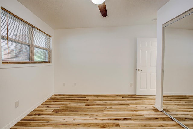unfurnished bedroom featuring baseboards, a ceiling fan, light wood finished floors, and a closet