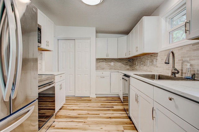 kitchen with tasteful backsplash, light wood-style flooring, stainless steel appliances, and a sink