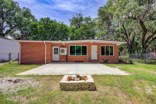 view of front of property featuring an outdoor fire pit, fence, entry steps, a front yard, and brick siding