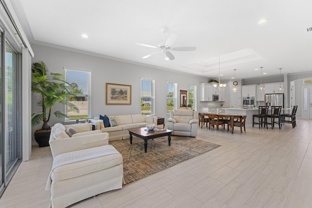 443 Pescado Dr, Saint Augustine, FL 32095 - living room featuring a raised ceiling, crown molding, ceiling fan with notable chandelier, and a wealth of natural light