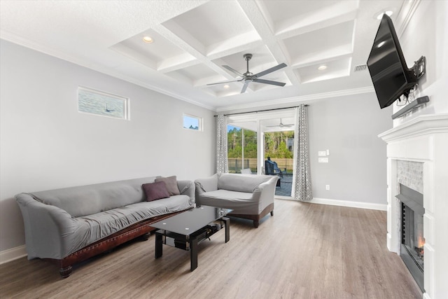 living room with ceiling fan, a tile fireplace, beamed ceiling, coffered ceiling, and light hardwood / wood-style flooring