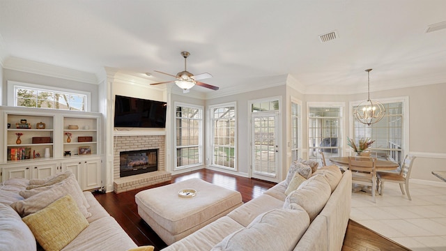 living room with a brick fireplace, visible vents, dark wood-style floors, and crown molding