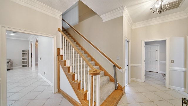 staircase featuring tile patterned flooring, arched walkways, a chandelier, and ornamental molding