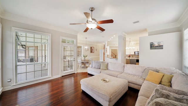 living area featuring baseboards, stairway, ornamental molding, dark wood-style flooring, and ceiling fan with notable chandelier