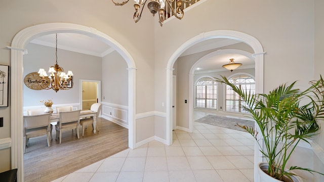 interior space featuring light tile patterned floors, a high ceiling, ornamental molding, and a notable chandelier