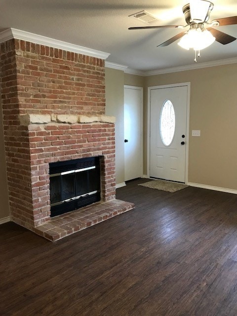 interior space featuring ceiling fan, a brick fireplace, dark hardwood / wood-style floors, and crown molding