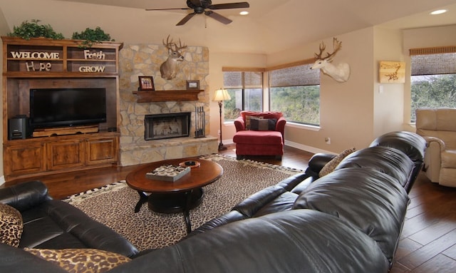 living room with ceiling fan, dark wood-type flooring, and a stone fireplace