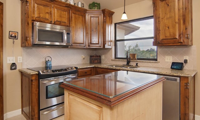 kitchen with backsplash, appliances with stainless steel finishes, sink, light stone counters, and pendant lighting