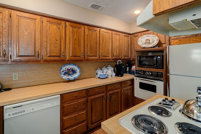 kitchen with tasteful backsplash, white appliances, and a textured ceiling