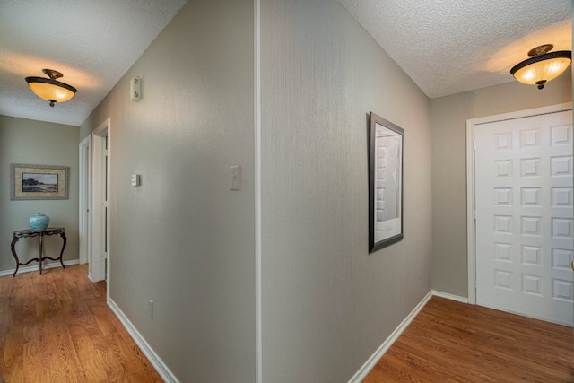 hall featuring a textured ceiling and light hardwood / wood-style floors