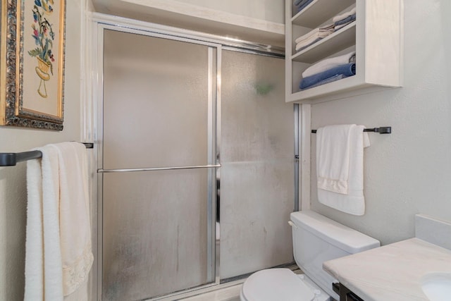 bathroom with toilet, a shower with shower door, and vanity