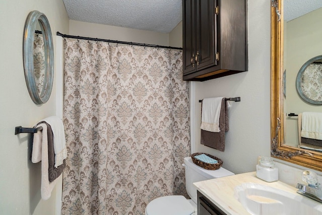 bathroom with toilet, vanity with extensive cabinet space, and a textured ceiling