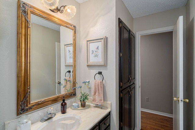 bathroom featuring a textured ceiling, wood-type flooring, and vanity with extensive cabinet space