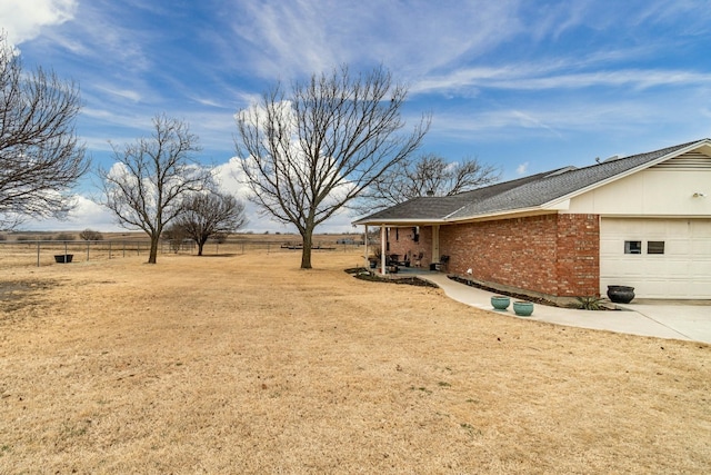 view of yard with a rural view and a garage