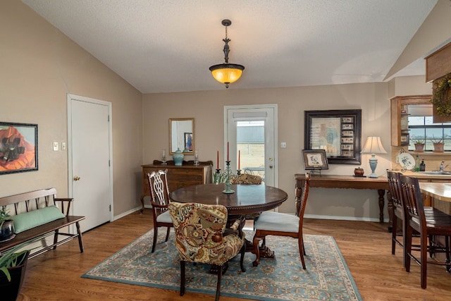 dining area featuring light wood-type flooring and vaulted ceiling