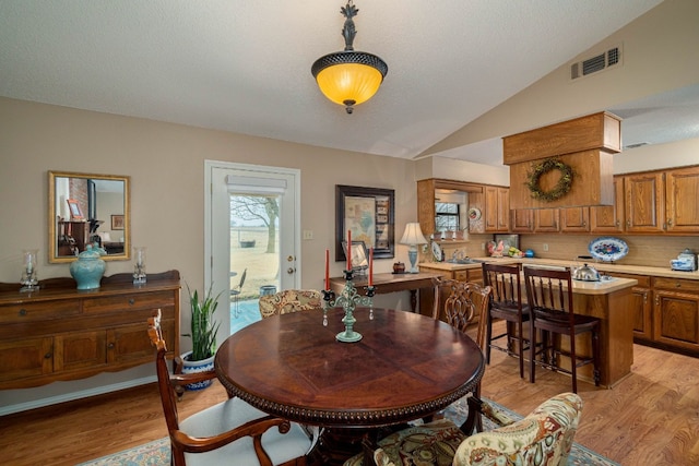 dining room with light wood-type flooring and lofted ceiling