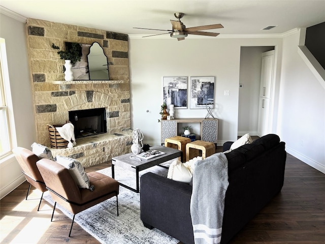 living room featuring crown molding, a fireplace, ceiling fan, and dark wood-type flooring