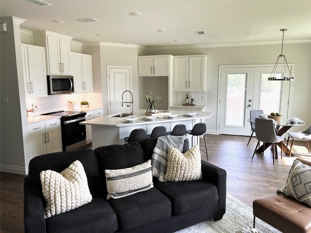 living room featuring crown molding, wood-type flooring, french doors, and sink