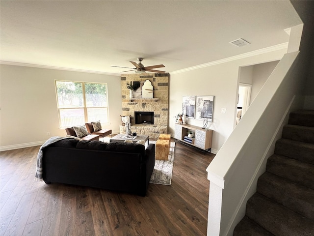 living room featuring crown molding, a stone fireplace, and dark hardwood / wood-style floors