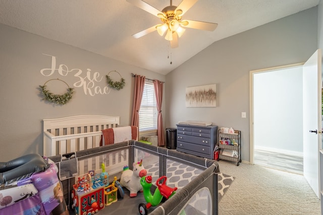 bedroom with carpet flooring, a nursery area, ceiling fan, and vaulted ceiling