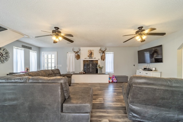 living room featuring ceiling fan, dark hardwood / wood-style floors, and a textured ceiling