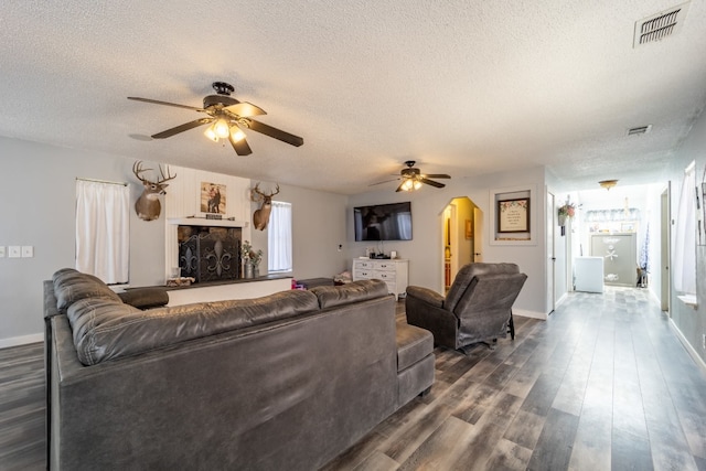 living room featuring ceiling fan, dark hardwood / wood-style flooring, and a textured ceiling