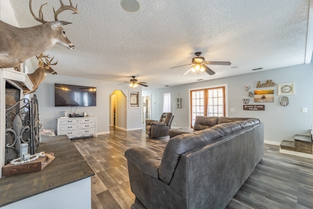 living room with a textured ceiling, a fireplace, and dark wood-type flooring