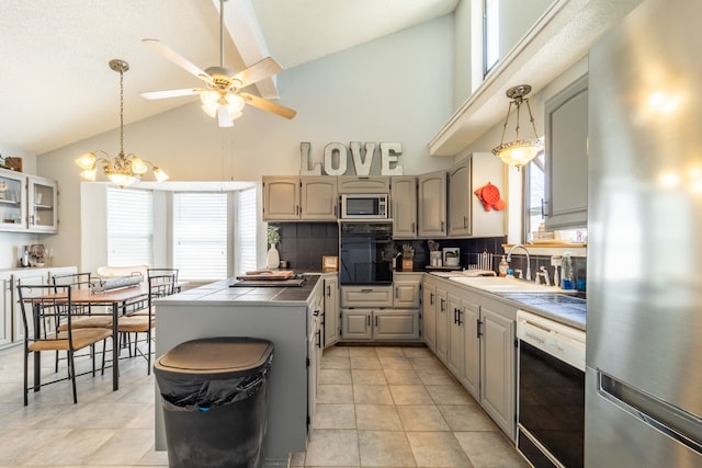 kitchen featuring sink, appliances with stainless steel finishes, high vaulted ceiling, tasteful backsplash, and ceiling fan with notable chandelier