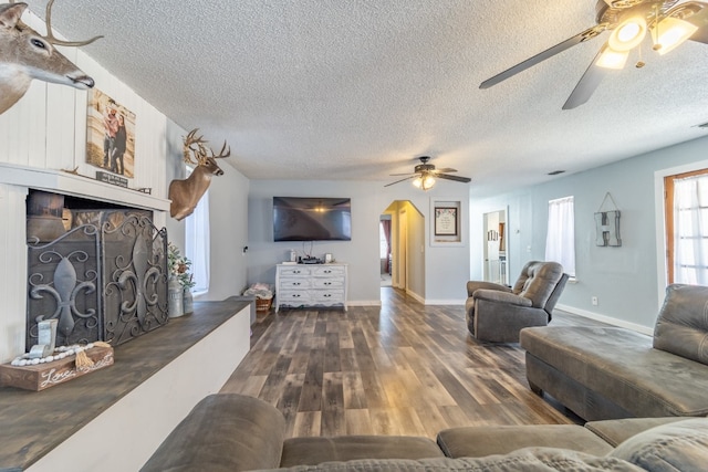 living room with dark hardwood / wood-style flooring, a textured ceiling, and ceiling fan