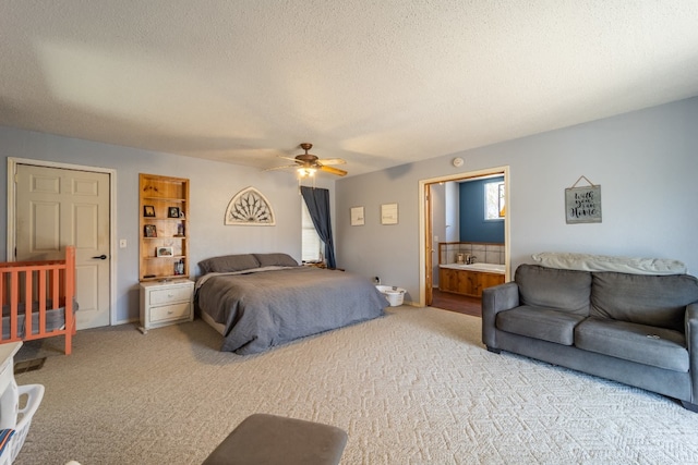 bedroom featuring ceiling fan, light colored carpet, ensuite bathroom, and a textured ceiling