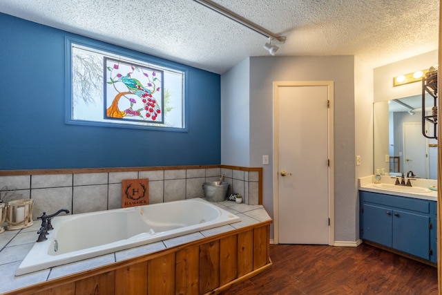 bathroom featuring a textured ceiling, large vanity, hardwood / wood-style floors, and a washtub