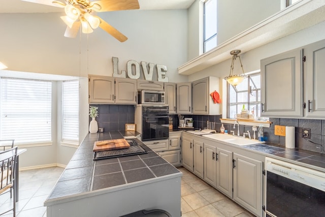 kitchen with oven, backsplash, stainless steel microwave, sink, and dishwasher