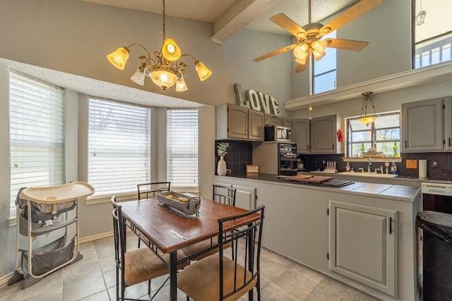 kitchen featuring tasteful backsplash, a towering ceiling, light tile floors, tile countertops, and ceiling fan with notable chandelier