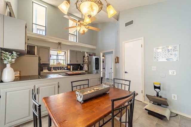 tiled dining area featuring sink, ceiling fan, and a towering ceiling