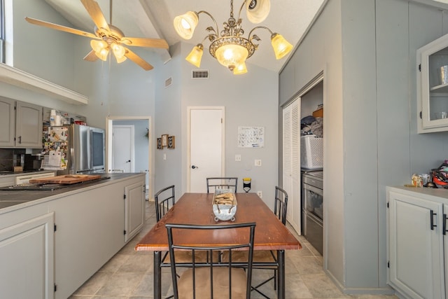 kitchen featuring light tile floors, lofted ceiling, tasteful backsplash, and ceiling fan with notable chandelier