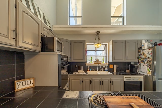 kitchen with tile counters, pendant lighting, sink, stainless steel appliances, and tasteful backsplash