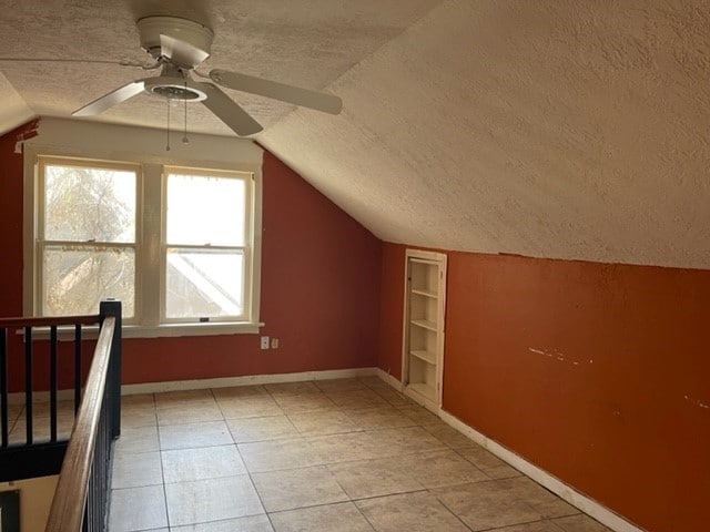 bonus room with ceiling fan, a textured ceiling, light tile floors, and vaulted ceiling