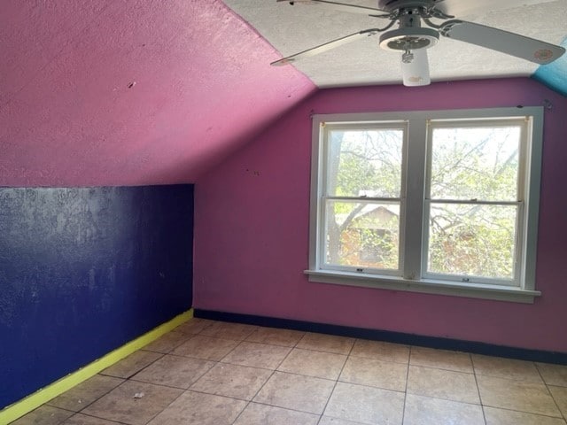 bonus room with lofted ceiling, light tile floors, ceiling fan, and a textured ceiling