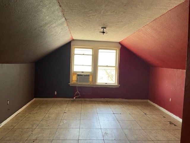 additional living space featuring a textured ceiling, vaulted ceiling, and light tile floors