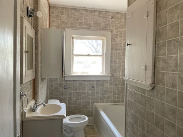 full bathroom featuring toilet, oversized vanity, shower / tub combination, tile walls, and tile flooring