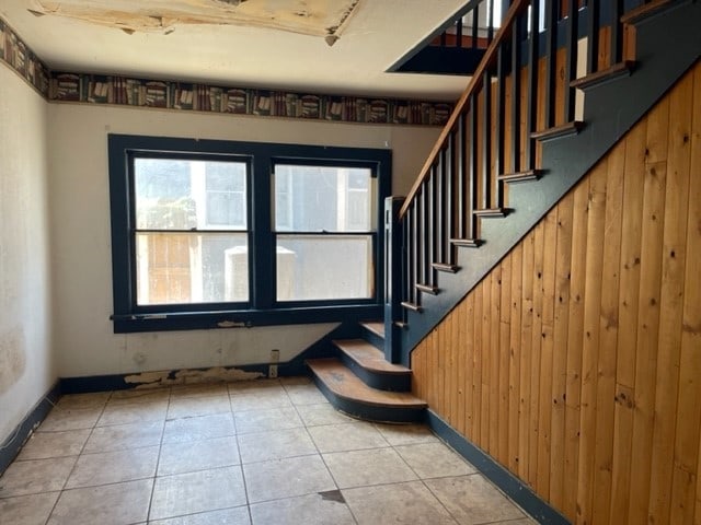 staircase with wooden walls and light tile flooring