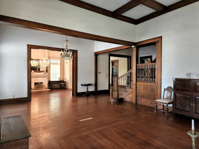 empty room featuring coffered ceiling, an inviting chandelier, dark hardwood / wood-style floors, and beam ceiling