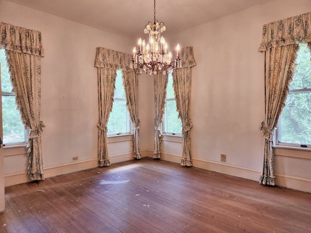 unfurnished room with a notable chandelier and dark hardwood / wood-style flooring