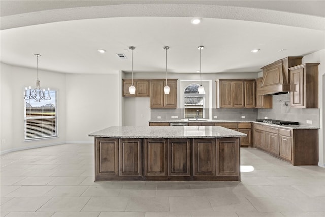 kitchen with a center island, a chandelier, premium range hood, and pendant lighting